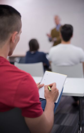 male student taking notes in classroom male student taking notes in classroom. business education concept, casual young businessman on seminar training